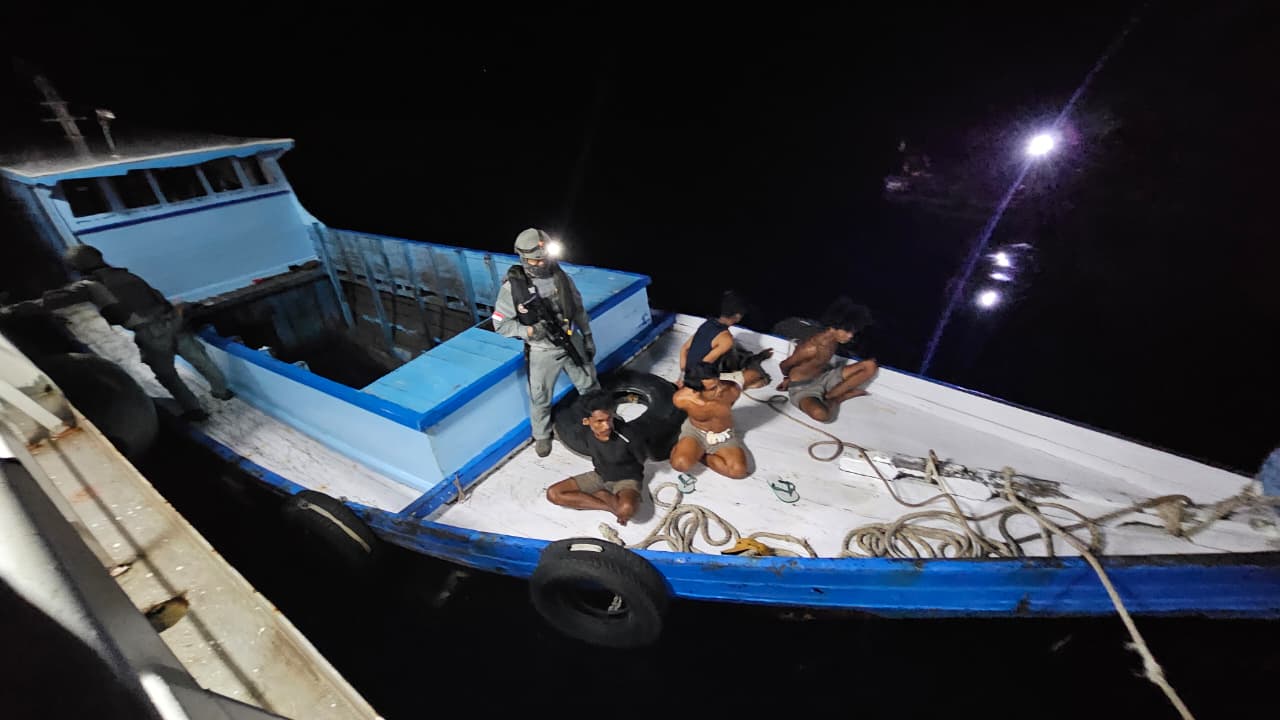 Personel Bakamla bersenjata mengamankan lima terduga pelaku dalam operasi penangkapan perompak Kaltim di malam hari.